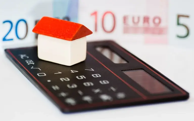 Symbolbild zur Immobilienfinanzierung mit Modellhaus und Taschenrechner